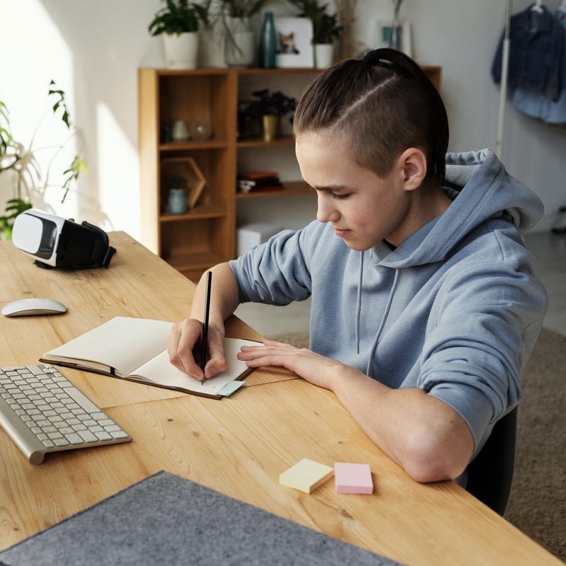 boy-in-gray-hoodie-while-writing-on-hok-4144531